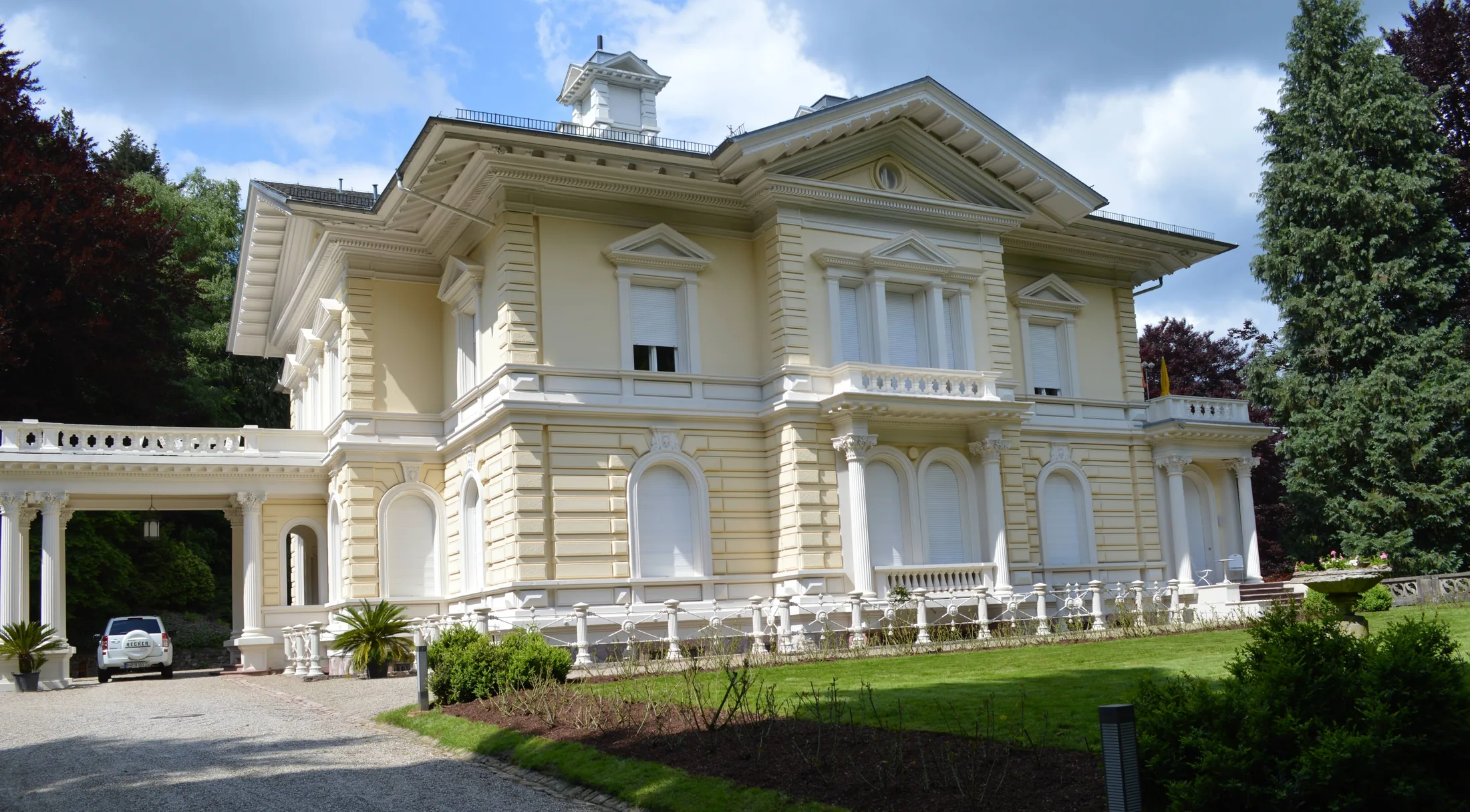 Weiße historische Villa mit Säulenvorbau und Belvedere im Park